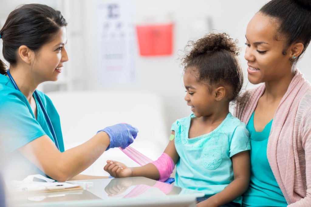 A nurse caring for a young child, with the child’s mother nearby