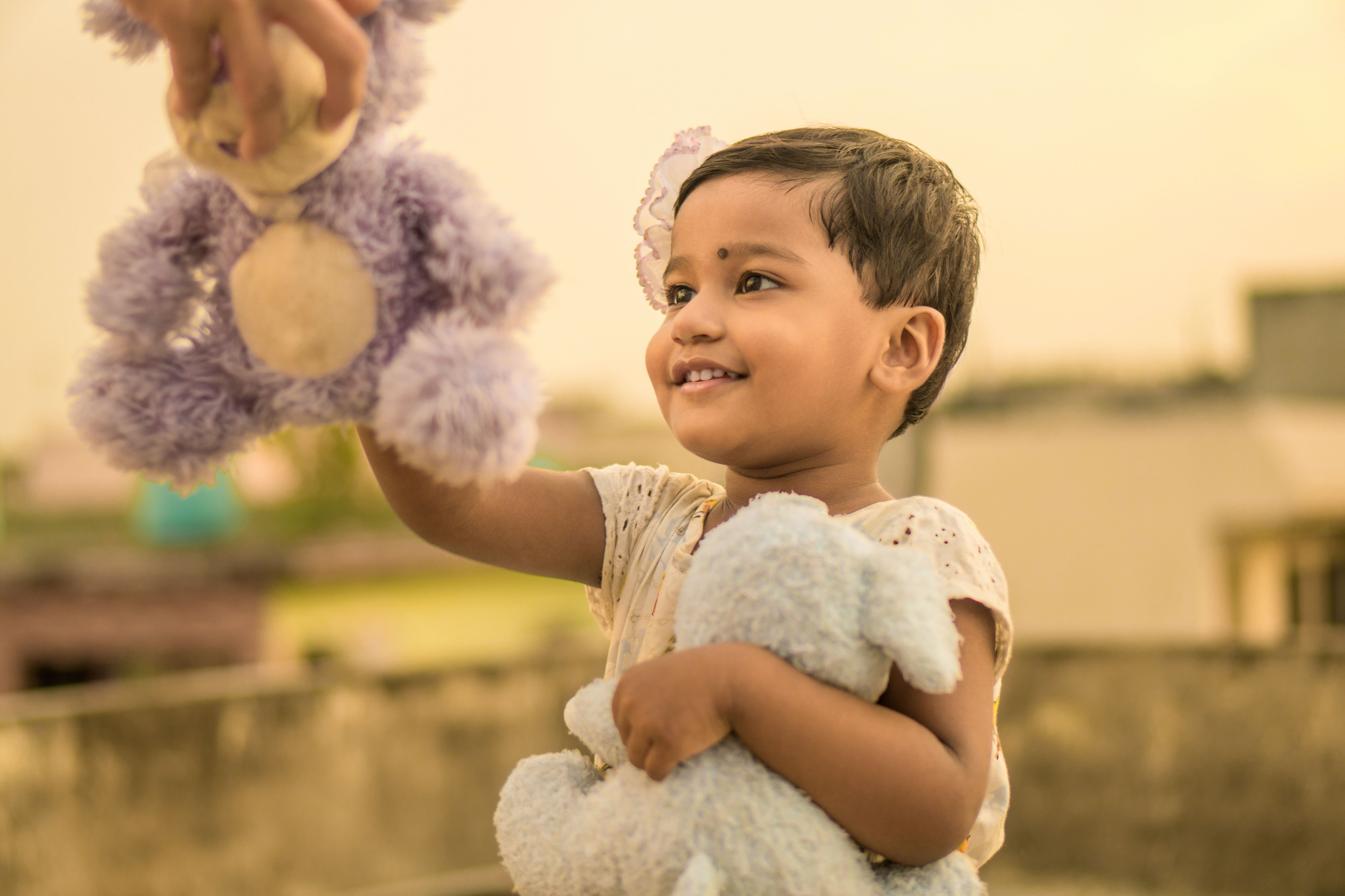 A smiling young child holding a soft toy